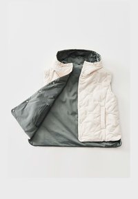 Ärmellose gesteppte Weste mit Kapuze, cremefarbener Außenstoff, dunkelgraues glattes Innenfutter, Druckknöpfe und Seitentaschen, flach ausgelegt und teilweise geöffnet.