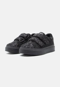 Sneakers neri con texture glitterata, due cinturini regolabili a strappo e suole spesse in gomma su sfondo bianco semplice.