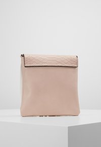 Hellrosa Lederhandtasche mit einer strukturierten, gemusterten Klappe. Glatter Körper mit minimalistischem Design. Verfügt über einen magnetischen Verschluss.