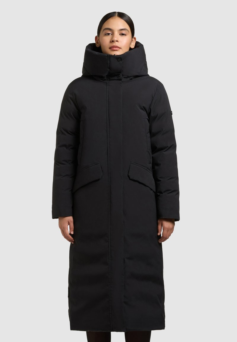 Sort lang pufferjakke med høj krave, der har to forlommer og en lige silhuet. Lavet af glat, isolerende stof.