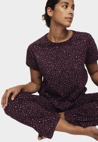 Bordeaux pyjamasæt med korte ærmer og cropped bukser, prydet med et pink leopardmønster. Blødt stof, løs pasform og rund halsudskæring.