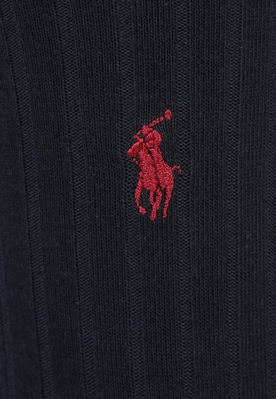 Tumesinine soonik, millel on vasakul küljel punane tikitud polo mängija logo, pehme tekstuur ja istuv disain.