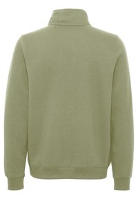 Sudadera verde con cuello alto, mangas largas y puños acanalados. Fabricada con un tejido suave y texturizado, de corte relajado.
