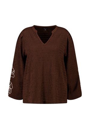 Blouse manches longues marron texturée avec col en V et broderie florale blanche sur les manches, taille moyenne, coupe ample.