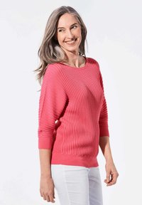 Koralfarbener Rippstrickpullover mit Dreiviertelärmeln, Rundhalsausschnitt und eng anliegenden Manschetten. Strukturdesign über das gesamte Kleidungsstück mit glattem Saum.