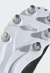 Zwart-witte voetbalschoen zool met zes metallic noppen, een gladde plastic textuur en aerodynamische ontwerpcontouren.