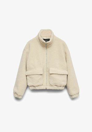 Chaqueta corta beige de material acolchado, con cuello alto, cierre frontal de cremallera y dos grandes bolsillos delanteros.