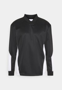 Haut de sport noir à manches longues avec un col montant, des panneaux latéraux blancs, une texture lisse et des poignets côtelés contrastants.