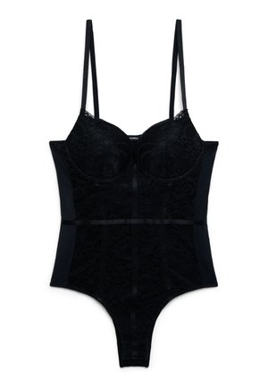 Czarny koronkowy body z cienkimi regulowanymi ramiączkami, miseczkami z fiszbinami oraz satynową kokardą w talii, sfotografowane na białym tle.