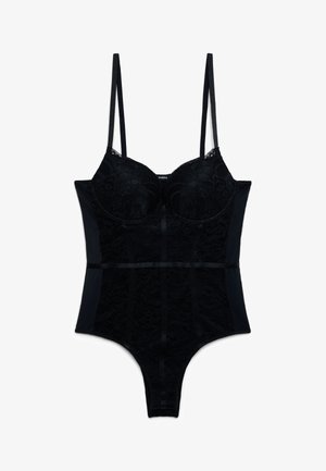 Czarny koronkowy body z cienkimi regulowanymi ramiączkami, miseczkami z fiszbinami oraz satynową kokardą w talii, sfotografowane na białym tle.