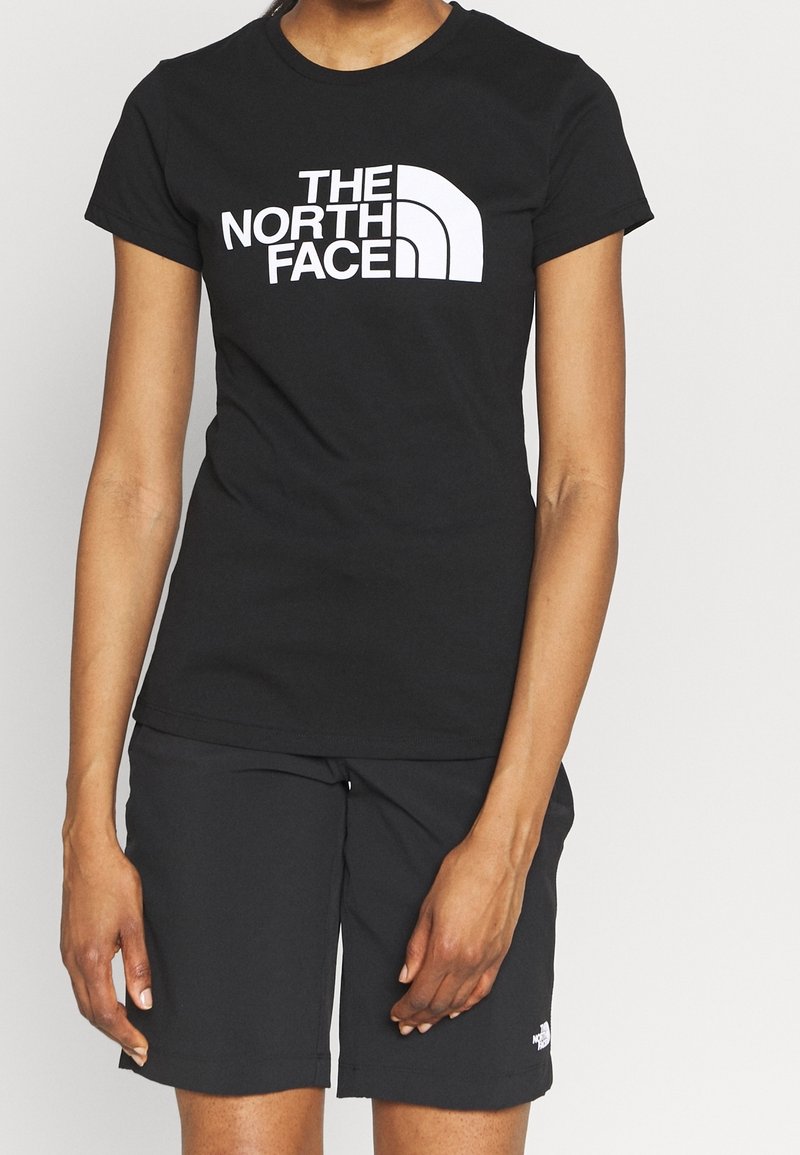 Svart T-shirt med en vit logo som står "THE NORTH FACE" på framsidan; kombinerat med svarta shorts, båda längst fram gjorda av ett slätt tyg.