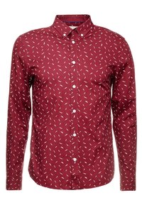 Camisa roja de manga larga con un patrón blanco similar a plumas, cuello abotonado y botones en la parte delantera. Material de algodón con una textura suave.