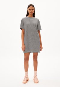 Gestreiftes T-Shirt-Kleid aus schwarzer und weißer Baumwolle, lockere Passform, mit kurzen Ärmeln und Rundhalsausschnitt, kombiniert mit rosa Sneakers und Socken.