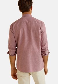 Camicia da uomo a maniche lunghe di colore rosa chiaro con un delicato motivo strutturato. Presenta un colletto classico e polsini arrotolati. Tessuto morbido in cotone.