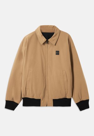 Casaco bege com fecho zip, punhos e barra pretos, gola, dois bolsos laterais e um pequeno logo EA7 no peito esquerdo.