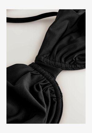 Zwarte bikini-top met geplooide stof voor textuur, verstelbare bandjes en gladde naden. Focus op comfort en een veilige pasvorm.