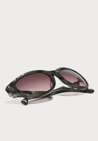 Melnas un pelēkas marmora saulesbrilles ar ovālām lēcām, pārejošu purpursarkanu tonējumu, elegantu dizainu un sudraba aksesuāriem uz tempļiem.