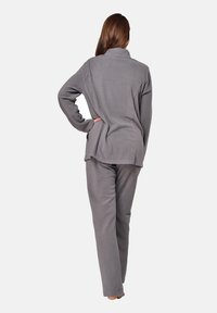 Graues Fleece-Loungewear-Set mit einem kragenlosen Jackett und geraden Hosen, weichem Material und lässiger Passform. Sichtbare Nahtdetails.