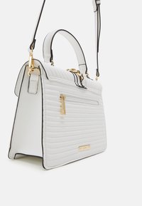 Vatteret hvid håndtaske med gulddetaljer, topgreb og aftagelig skulderrem. Rektangulær form med lynlåslomme foran.