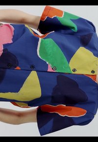 Kurzärmeliges Hemd mit Knöpfen und abstrakten großen Farbblöcken in Blau, Grün, Gelb, Rosa, Orange und Schwarz auf hellem Hintergrund.