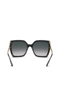 Lunettes de soleil carrées noires oversize avec verres dégradés gris foncé et chaîne décorative dorée sur les branches.