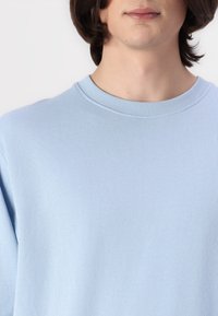 Lichtblauwe ronde hals trui van zacht, ribbelstof. Heeft een eenvoudig ontwerp met een gladde textuur en een relaxed fit.