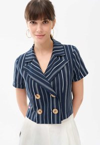 Marynarski, paskowany żakiet z krótkim rękawem, z podw ójnym zapięciem, drewnianymi guzikami i szerokim kołnierzem, wykonany z gładkiego materiału.