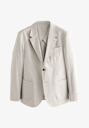 Svetlo béžové pánske sako z textúrovaného materiálu, s vrúbkovanými klopami, jedným čiernym gombíkom a náprsnými vreckami vpredu.