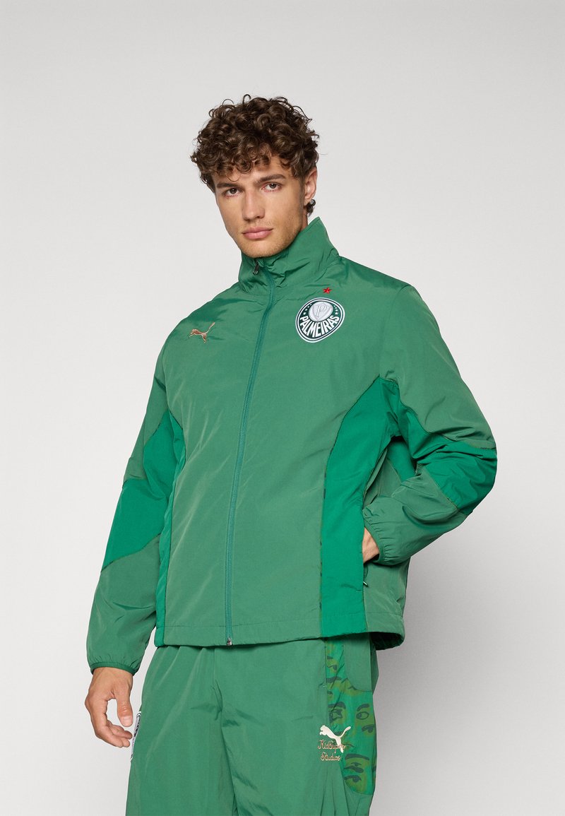 Grüne, mit Reißverschluss versehenen Jacke mit hohem Kragen, ausgestattet mit einem Logo auf der linken Brust und kontrastierenden Seitenpaneelen. Hergestellt aus glattem, leichtem Material.