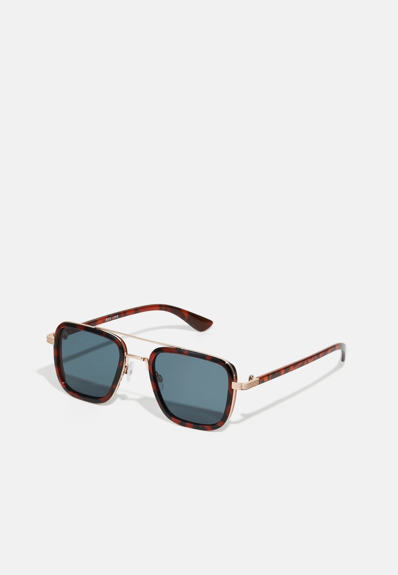 Gafas de sol de carey con lentes gris oscuro, forma cuadrada,accesorios de metal dorado y patillas delgadas con un distintivo detalle a rayas.
