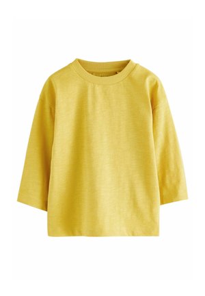 Haut en coton jaune avec un col rond, des épaules tombantes et des manches trois quarts ; texture douce et coupe décontractée.