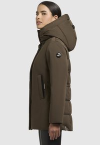 Brown insulated puffer jacket with a large hood, zip pockets, logo patch on the sleeve, and a quilted texture. Sleek, fitted design.