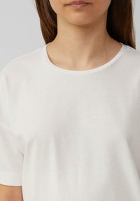 Witte katoenen T-shirt met een ronde hals en korte mouwen, met een gladde textuur en een eenvoudig ontwerp, minimale details.