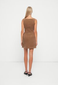 Braunes Kordkleid mit tailliertem Oberteil, ausgestelltem Rock und Reißverschluss auf der Rückseite. Verfügt über eine taillierte Taille und seitliche Taschen. Glatte Textur.