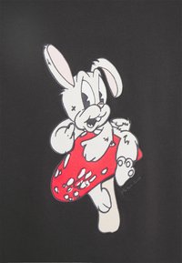 Zwarte stof met een cartoon van een witte konijn met roze accenten, die een rode paddenstoel met witte vlekken vasthoudt, omrand door zwart.