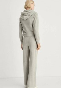 Light grey, soft fabric tracksuit featuring a hooded, cropped jacket and wide-leg pants. Smooth texture with a relaxed fit and no visible patterns.