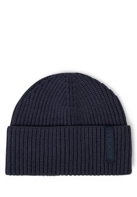 Dzianinowa granatowa czapka z prążkowanym teksturem i podwiniętym mankietem. Posiada naszywkę z logo z boku dla identyfikacji marki.