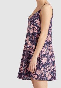 Kukkamekko, jossa on syvä V-pääntie, valmistettu kevyestä kankaasta. Siinä on vaaleanpunaisia ja kermaisia kukkakuvioita tummansinisellä taustalla.