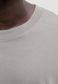 T-shirt gris à manches courtes avec un col rond, fabriqué en tissu de coton lisse avec des détails de couture fins et une texture douce.