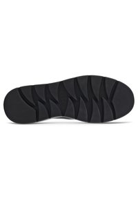 Semelle de chaussure en caoutchouc noir avec un motif de semelle ondulée et des bords surélevés pour l'adhérence. Présente un logo en relief près du talon.