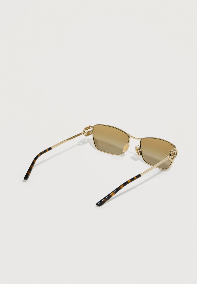 Lunettes de soleil rectangulaires à bordure dorée avec des verres teintés marron et des branches ornées d'un motif écaille de tortue sur fond blanc.