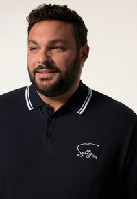 Námořnické polo tričko s bílým proužkovaným límcem a knoflíky. Obsahuje vyšívané logo "Salty Bay" na levé části hrudi. Materiál směs bavlny.