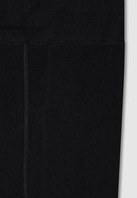 Czarne legginsy wykonane z elastycznej tkaniny o gładkiej fakturze. Posiadają szeroki, żebrowany pas i centralny szew.