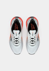 Pantofi sport albi cu partea superioară din plasă, interior negru și accente portocalii. Au șireturi și o talpă texturată pentru tracțiune. Logo-ul Reebok pe limbă.
