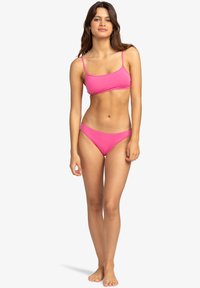 Conjunto de bikini de color rosa brillante que incluye un top bandeau con tirantes delgados y braguitas de corte bajo a juego, fabricado en una suave y elástica tela.