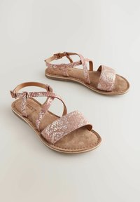 Rosaguldiga sandaler med korsade remmar, med ett metalliskt ormskinnsmönster. Syntetiskt fotbädd och justerbart ankeldetalj med spänne.
