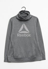Sudadera gris con cuello alto. Presenta un gran logo de Reebok en el centro y bolsillos laterales. Hecha de un material texturizado y elástico.