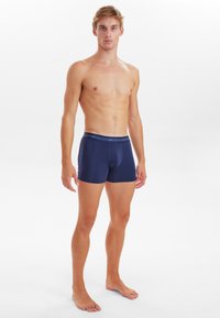 Dunkelblaue, baumwollene Boxershorts mit einem weichen Bund, anliegender Form und minimalistischer Gestaltung, ohne sichtbare Muster oder zusätzliche Akzente.