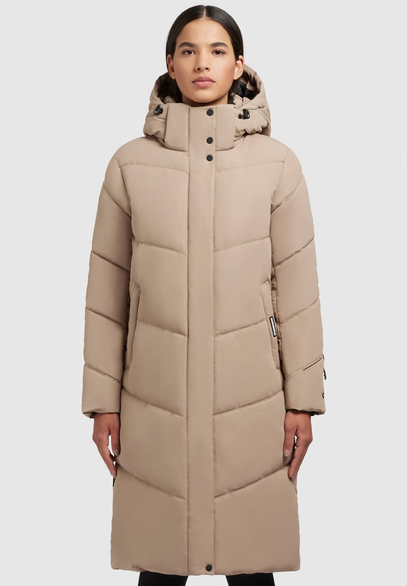 Palton lung bej, matlasat, cu glugă, având linii orizontale matlasate, nasturi tip snap și buzunare laterale cu fermoar. Textură netedă și design minimalist.
