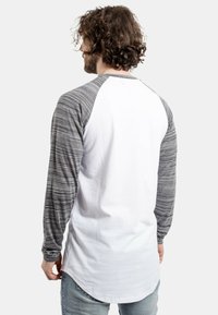 Hosszú ujjú raglan ing szürke melírozott ujjal és fehér teste. Puha pamut anyag, ívelt alsó résszel. Lazán elegáns dizájn.